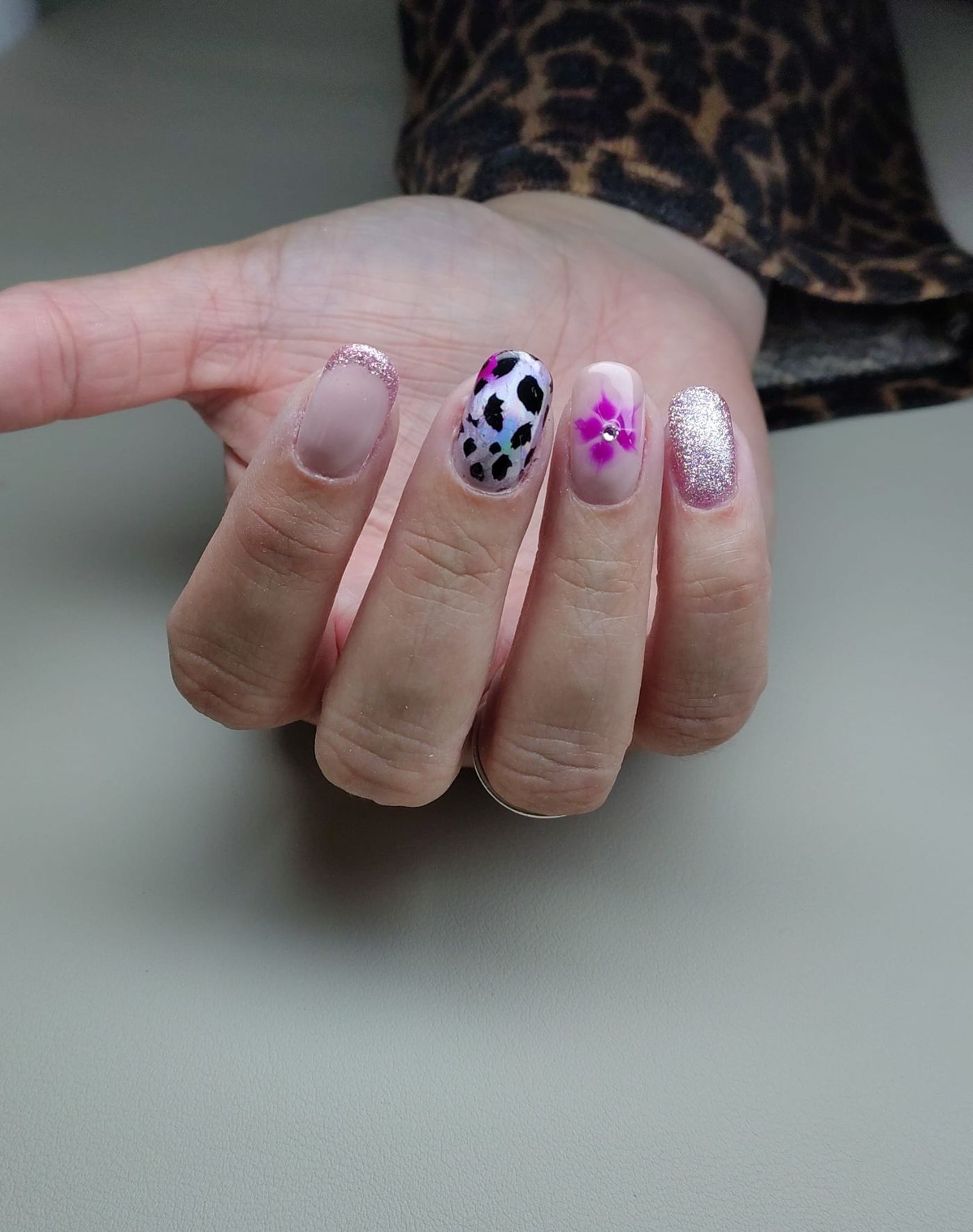Nail art met luipaardvlek, bloemetje en glitter op een lichte basis