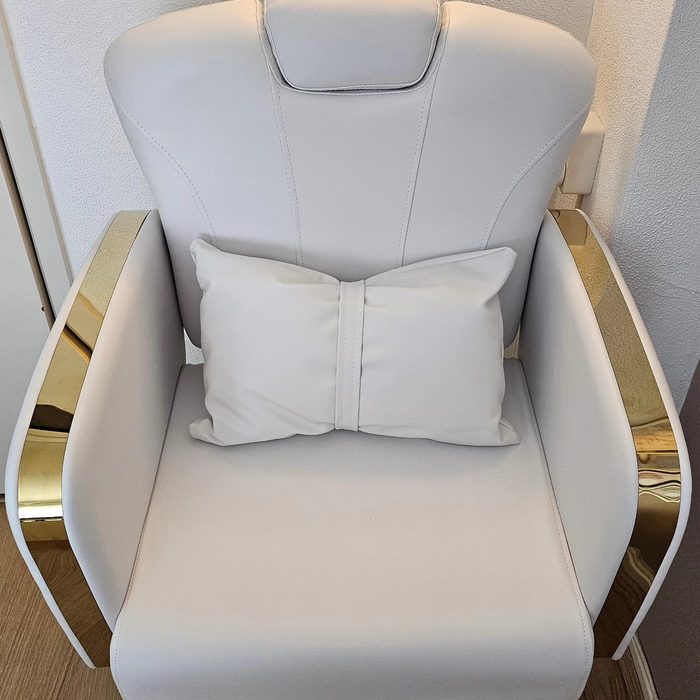De witte pedicurestoel met gouden zijkanten in de salon